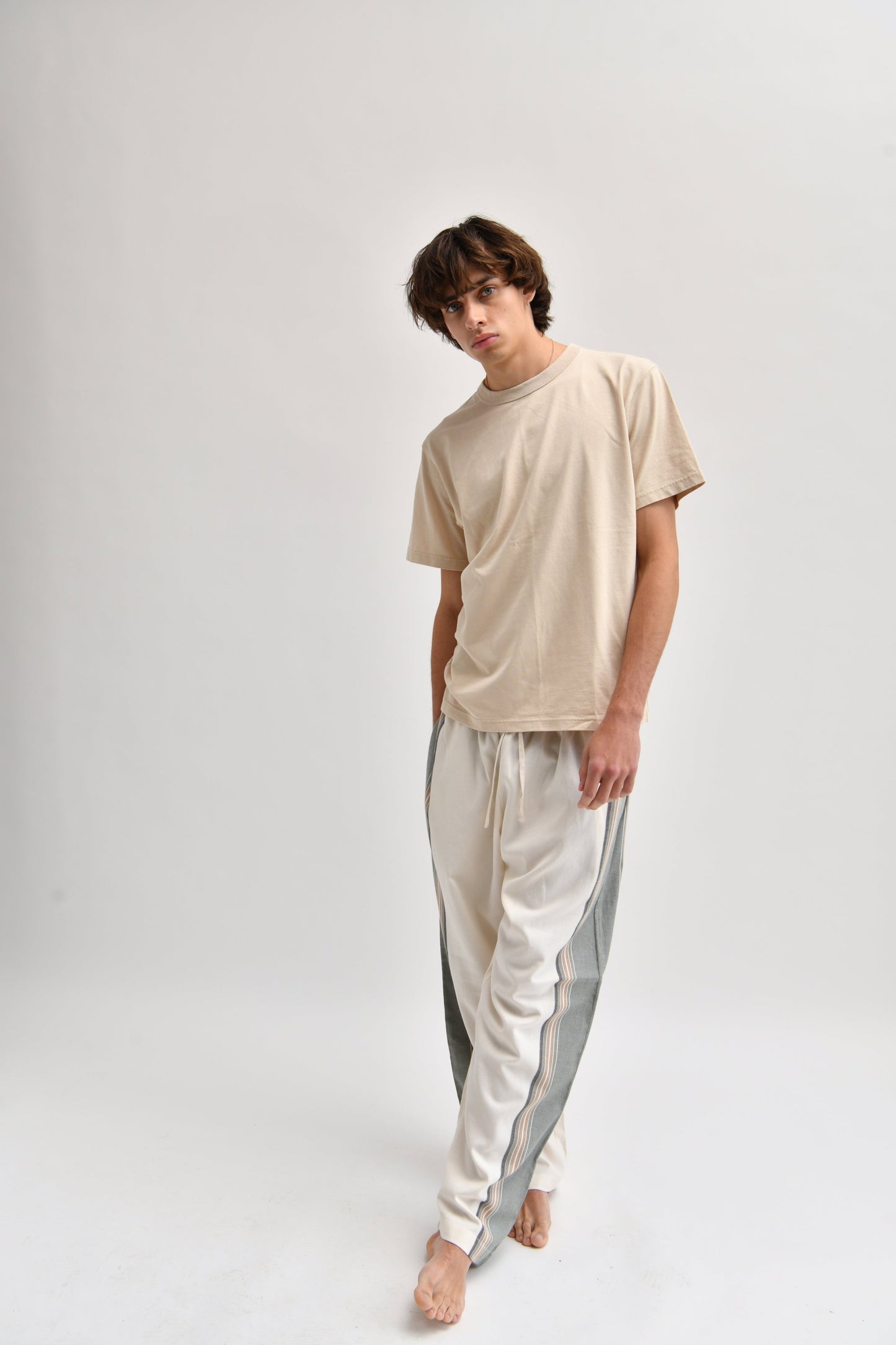 Front image of cream and khaki cotton trousers featuring a wide-leg, relaxed fit with a linen-style drape.