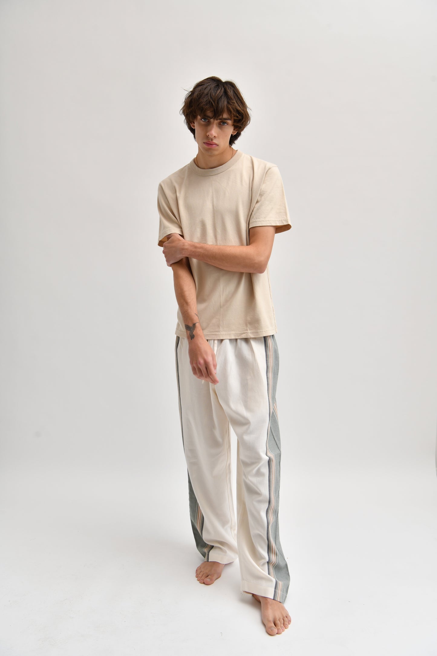 Front image of cream and khaki cotton trousers featuring a wide-leg, relaxed fit with a linen-style drape.